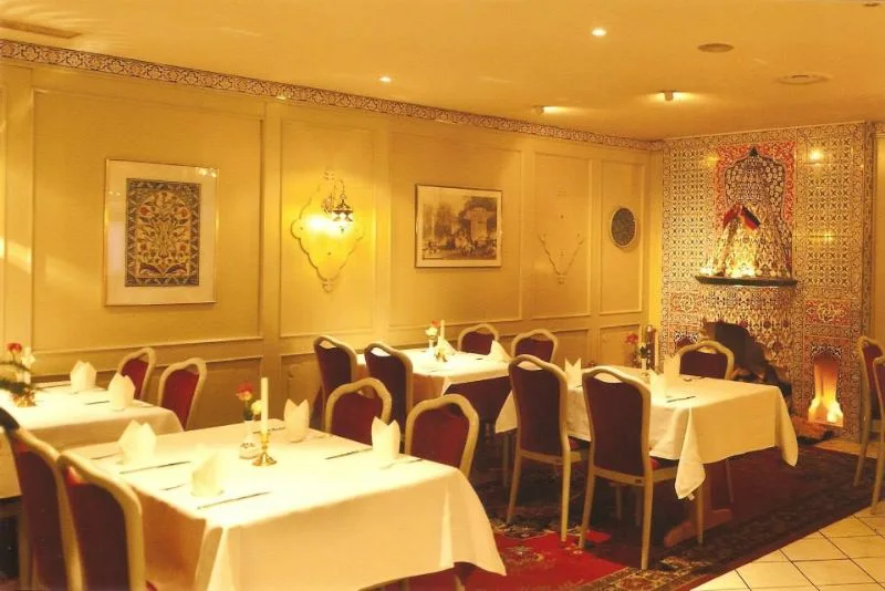 Gedeckte Tische vor einer dekorierten Wand im Restaurant